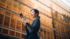 woman outside of an office building looking at her phone