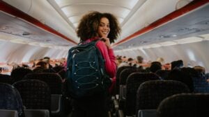 woman looking back at camera in an airplane with a backpack on