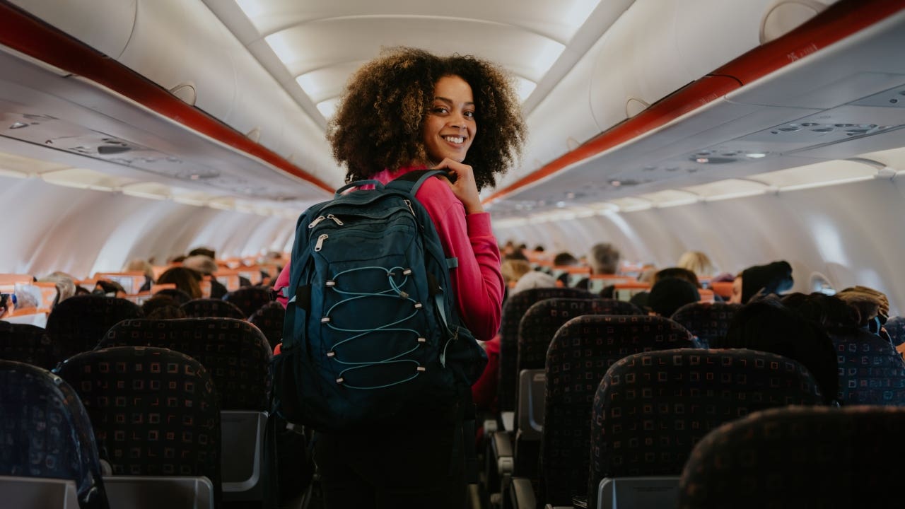 woman looking back at camera in an airplane with a backpack on