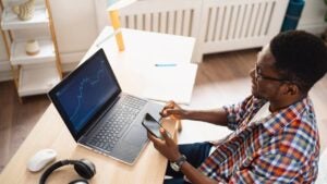 Person sitting at desk while looking at their laptop and smartphone.