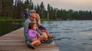 Grandparents and granddaughter enjoy sunset on a lake dock