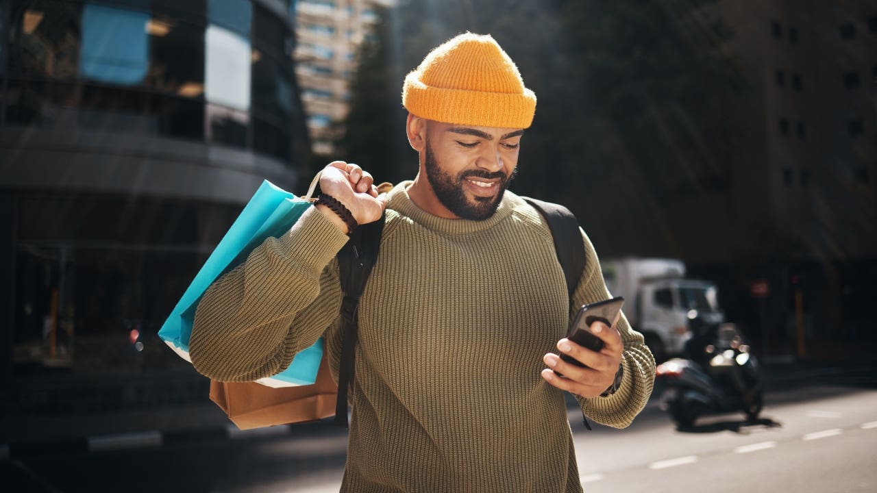 man holding shopping bags and looking at his phone