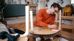 man sitting on the ground building furniture