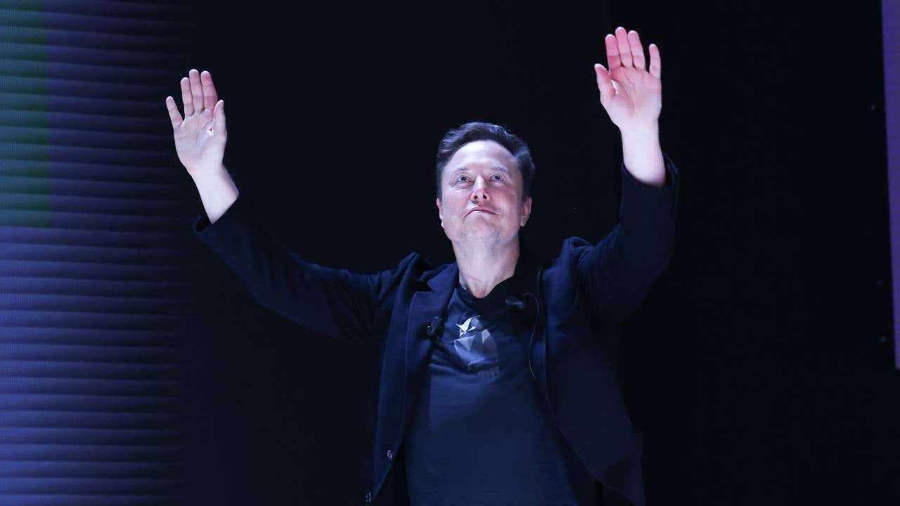 Elon Musk with his hands in the air.