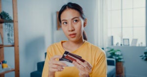 Young woman holding a stack of cards and thinking