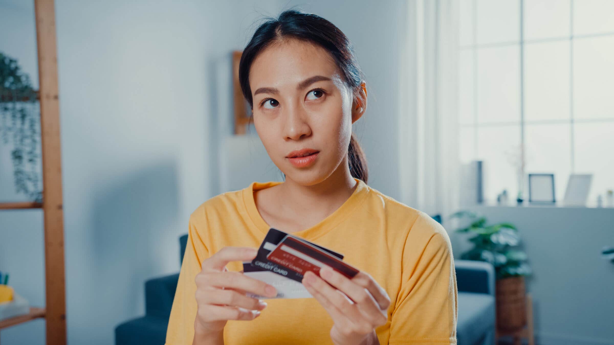 Young woman holding a stack of cards and thinking