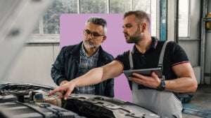 Two people looking at a car needing repairs