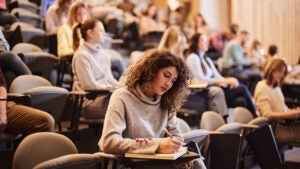 A young woman takes an exam in a college lecture hall.