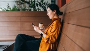 woman holding a coffee & looking at her phone