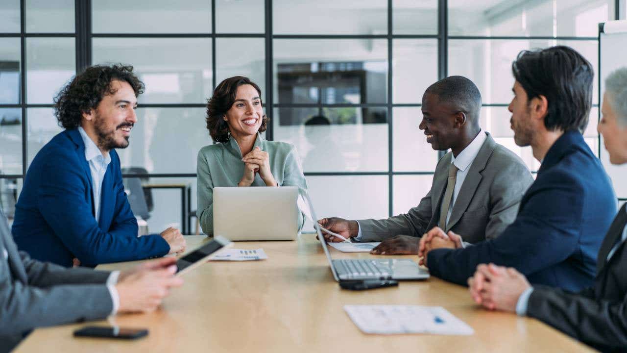 Six people sitting at a conference table in an office setting.