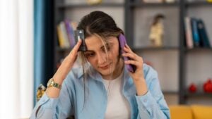 person holding phone and debit card and appears stressed