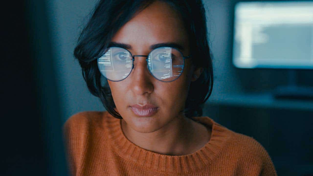 Person with computer code from a monitor being reflected in their glasses.