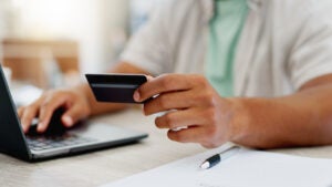 A person holding a credit card while on their laptop