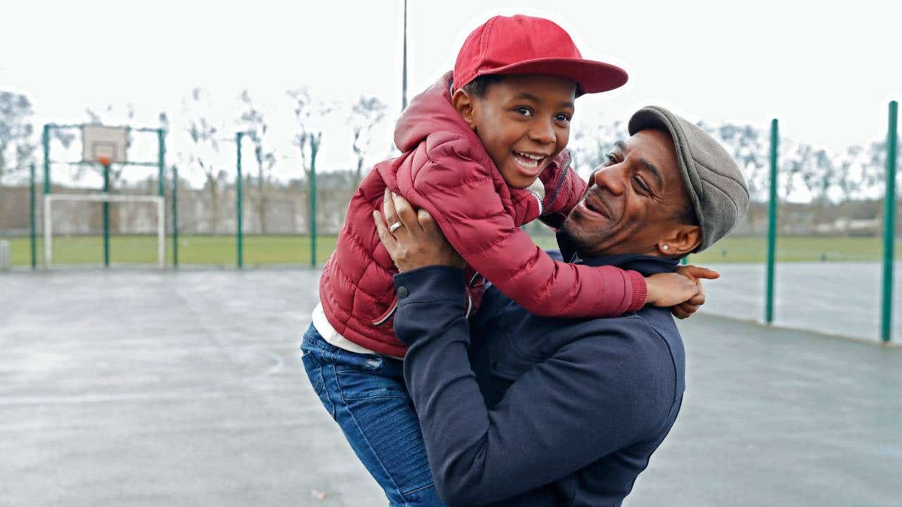 A father and son play in a park together.