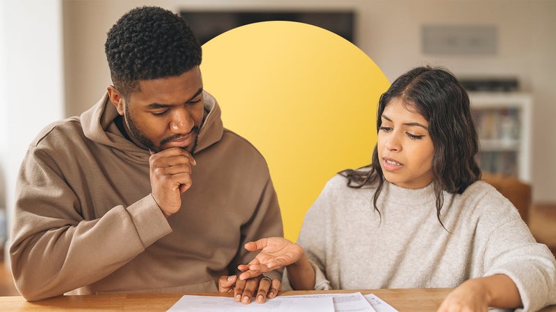 A couple sitting at a desk looking at financial documents with a design element behind them