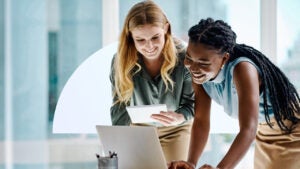 Two women look at a computer screen.