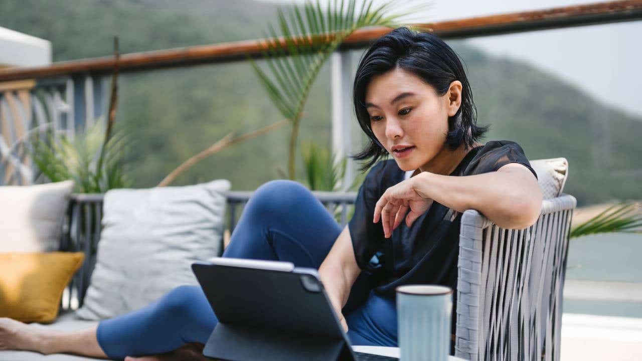 person looking at computer while sitting on balcony