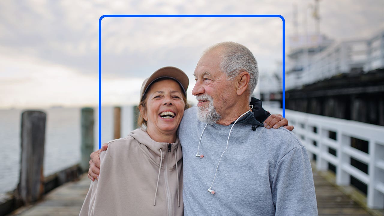 A retired couple walks down a boardwalk.