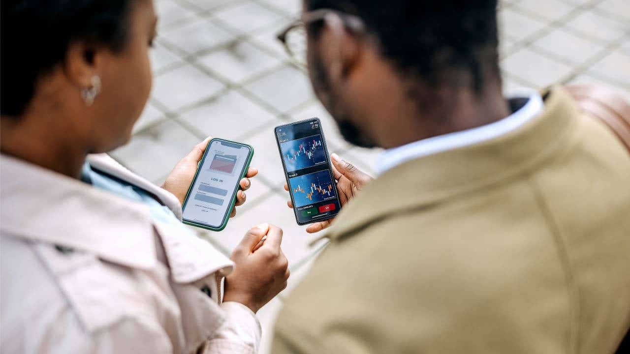 A man and woman check their crypto investments on their phones.