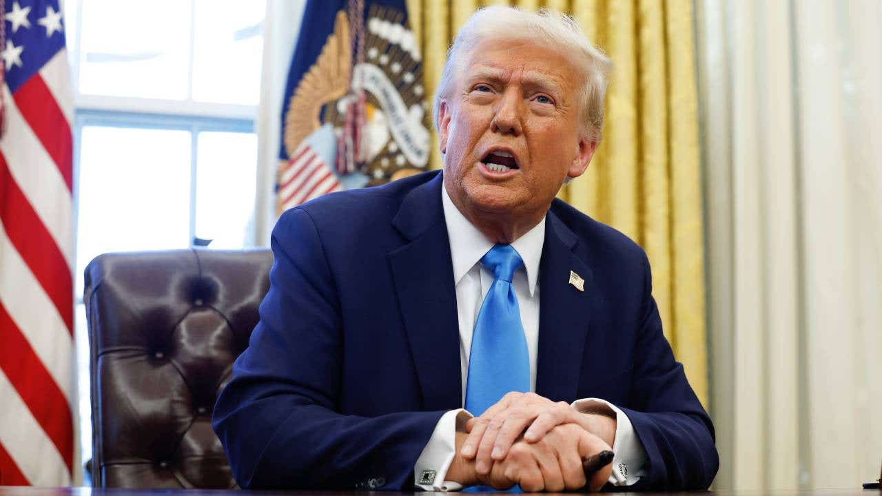 Donald Trump sitting at a desk in the Oval Office.