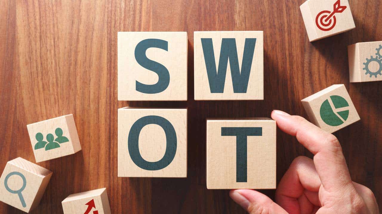 Putting wood cubes with alphabets and icons together to spell SWOT