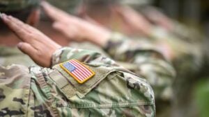 A line of U.S. soldiers saluting as seen from behind.