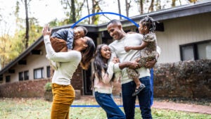 family laughing and photographed in front of their home