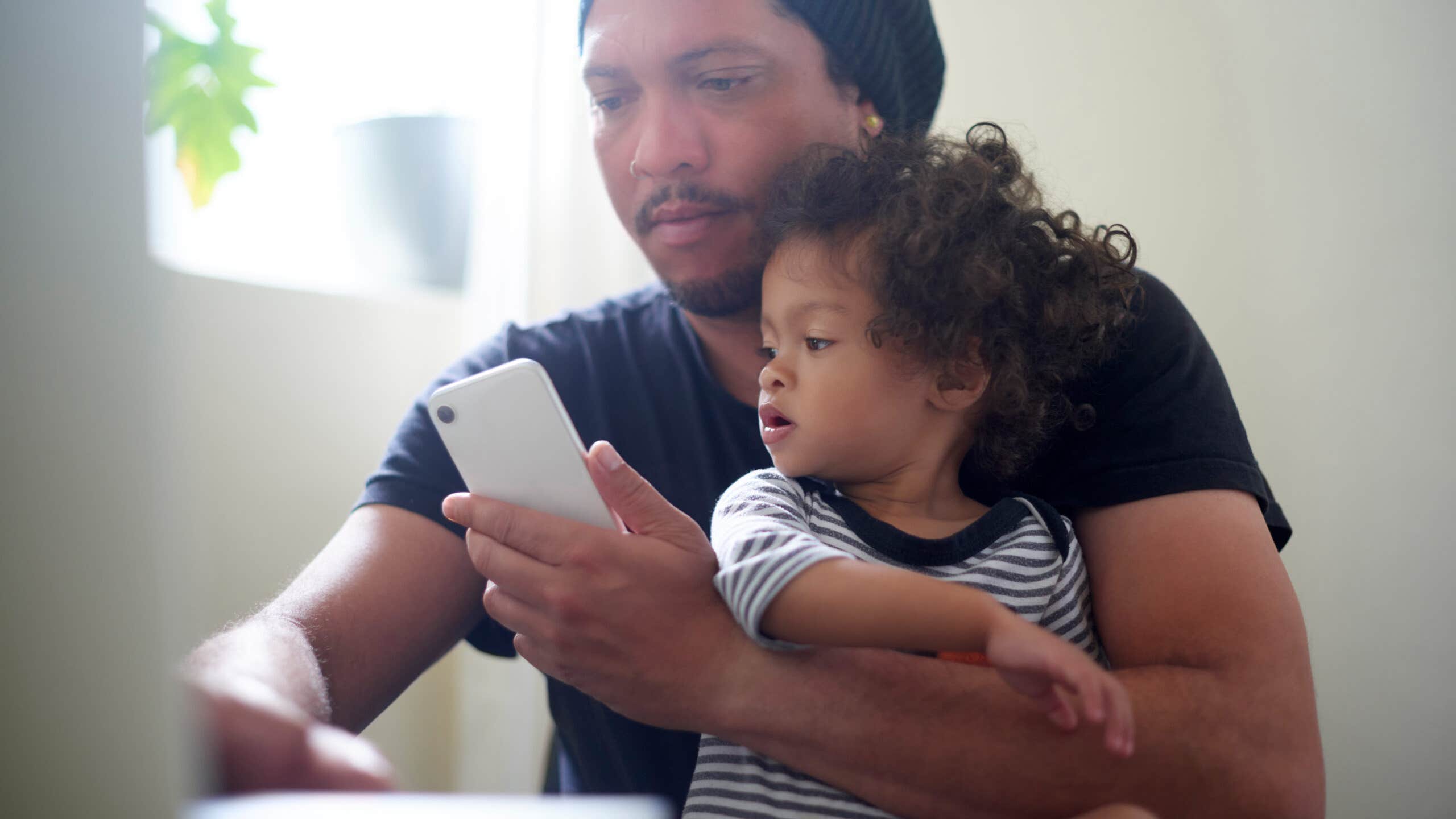 Man works on laptop while holding a child