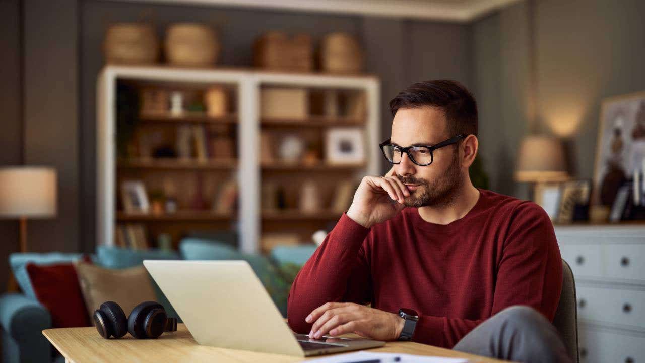 A young man looks at his laptop.