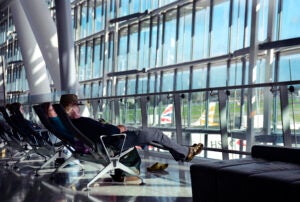 Travelers sit at airport gate looking out windows