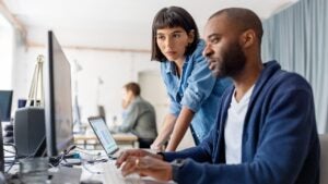 man and woman working together at a computer in an office