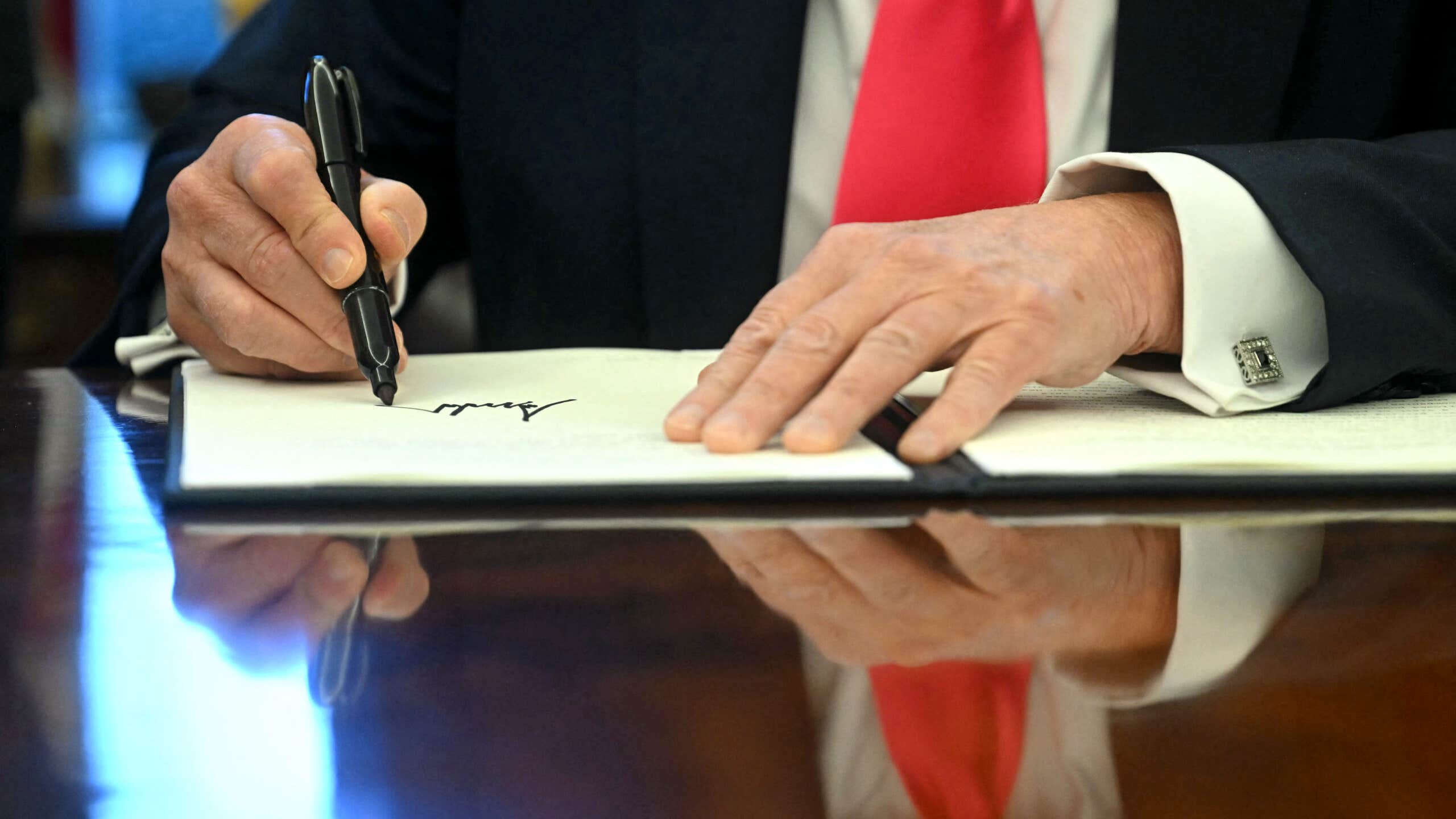 Close up of hands as Donald Trump signs executive order.