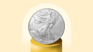 A silver coin sits on a gold pedestal.