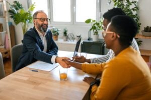 Grateful couple handshake with mortgage lender before signing contract