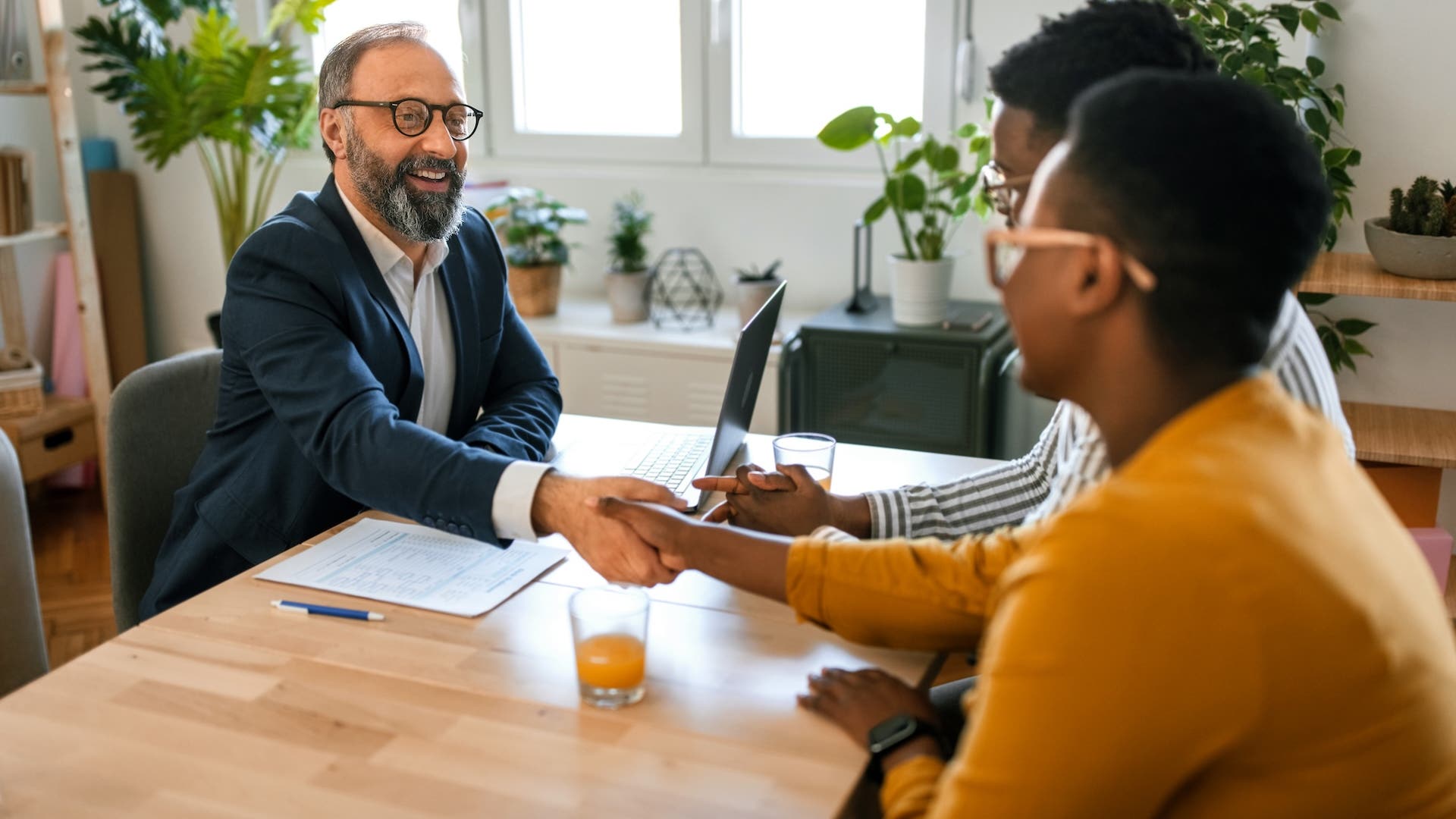 Grateful couple handshake with mortgage lender before signing contract