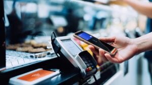 Close up of a woman's hand paying with her smartphone in a cafe