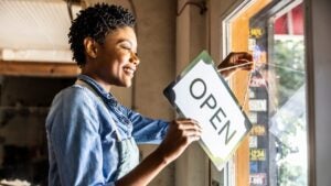 smiling woman flipping store sign to open