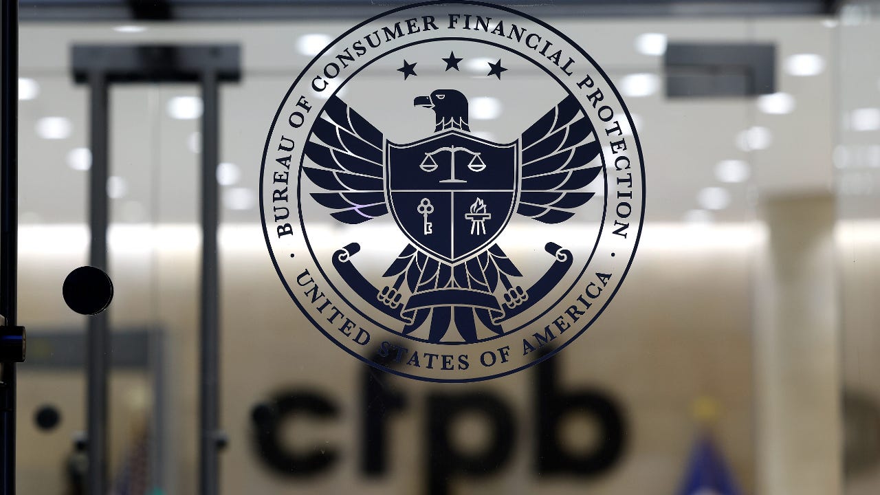 A picture of the CFPB logo on the glass door leading into a building.