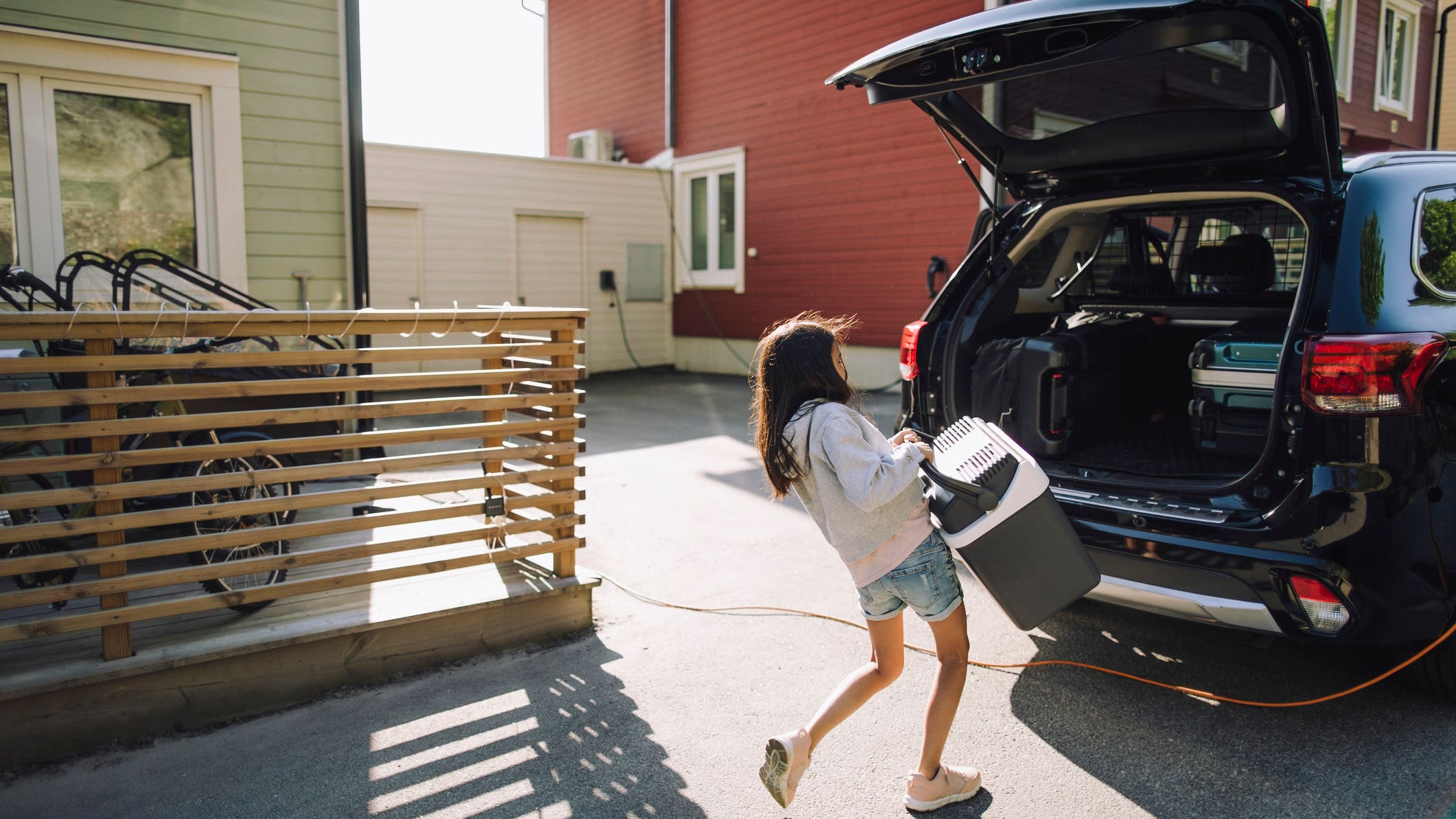 woman lifting cooler into black car