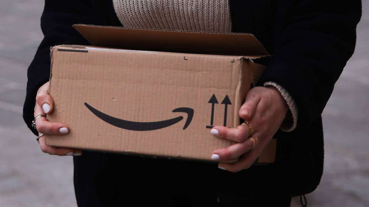 A woman holds an Amazon box.