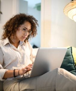 Woman sitting on her couch, looking at her laptop