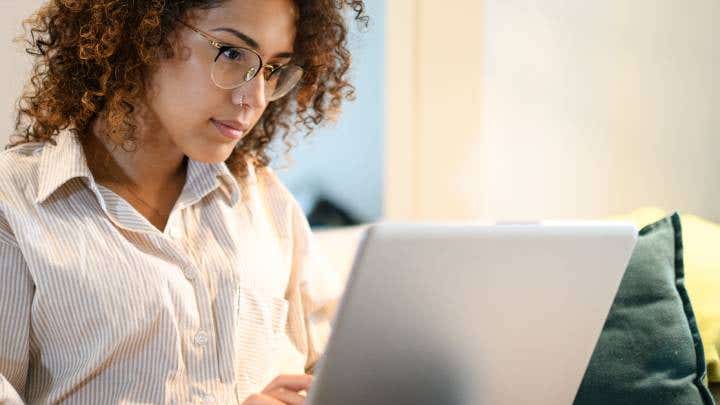 Woman sitting on her couch, looking at her laptop