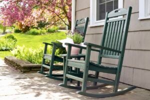 Two green rocking chairs on the porch of a residential home on spring day