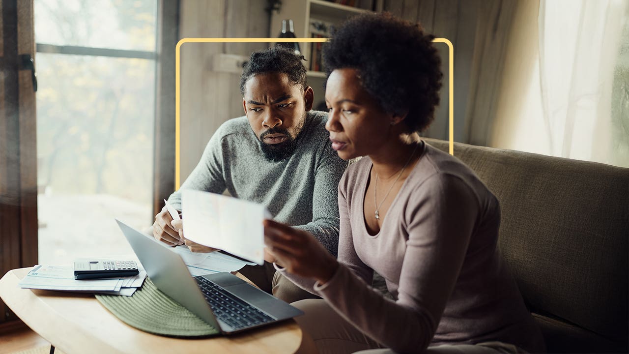 Two people sit at a computer and look at financial statements