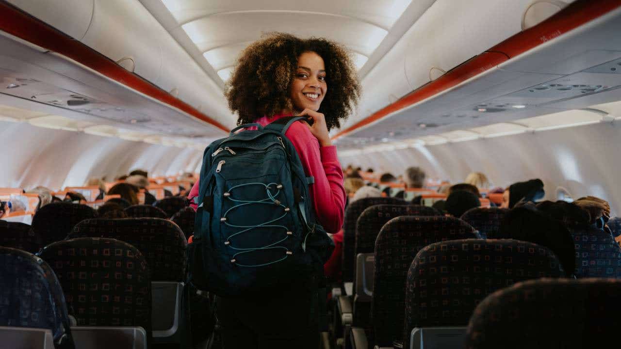 A woman boards a plane with her backpack.