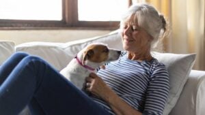 A senior woman plays with her dog at home.