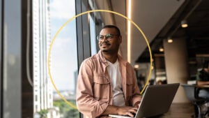 Person sitting at desk working on laptop with design element in the background