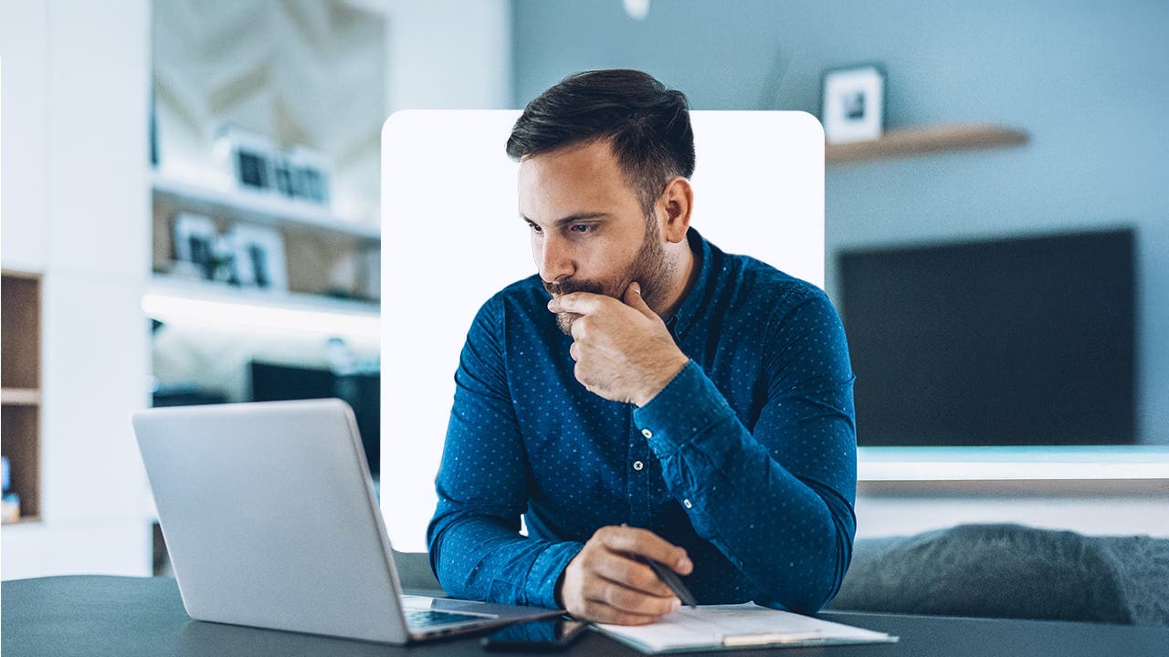 A man looks at a laptop screen contemplatively.