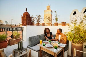 Wide shot of smiling couple dining at rooftop restaurant in the Medina of Marrakech while on vacation