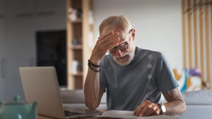 An elderly man looks anxious as he reviews a bill or statement.